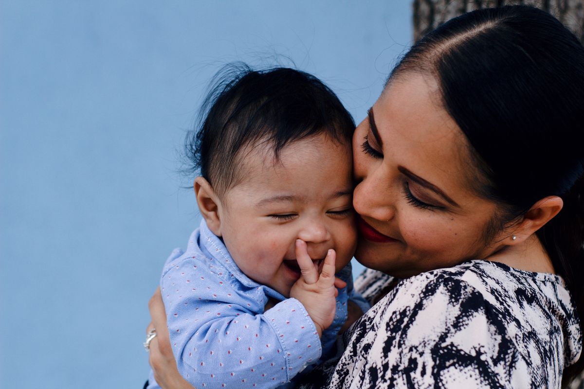 Una madre abraza mejilla con mejilla a su bebé sonriente