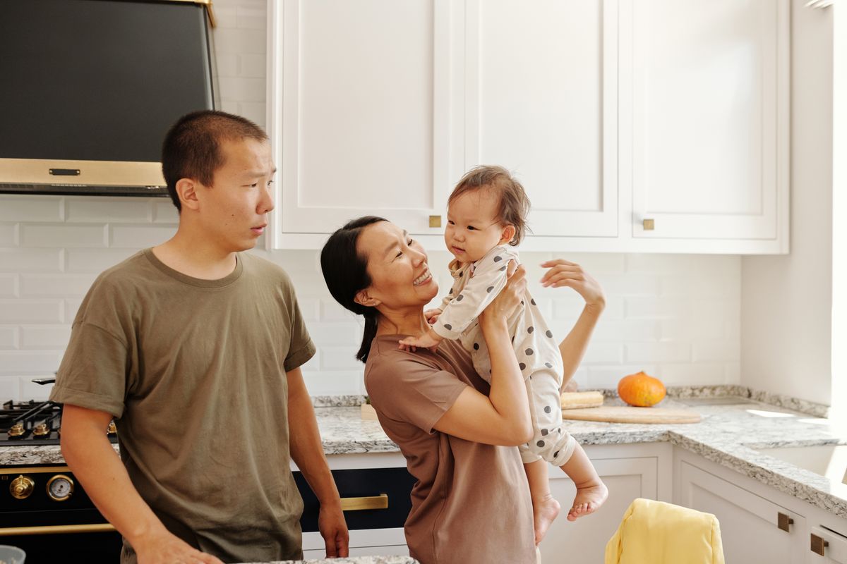 Una madre y un padre en la cocina con su bebé en brazos