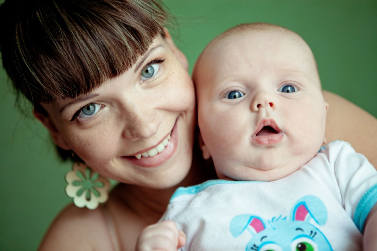 Una madre sonríe mejilla con mejilla junto a su bebé de ojos azules